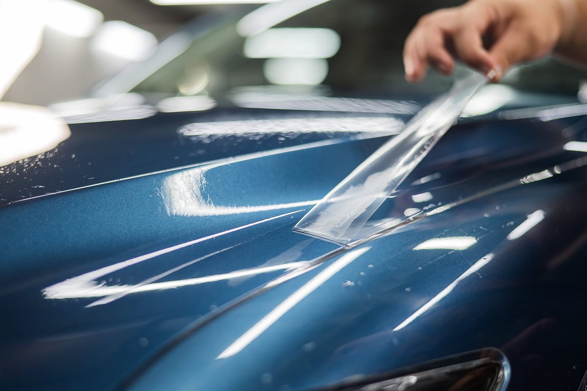 Master technician applying a protective armour film to a car body panel