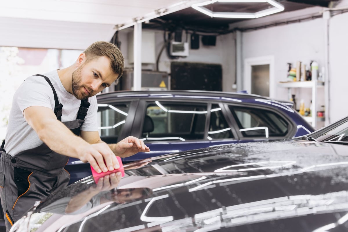 Specialist applying a polyurethane paint protection film to a vehicle body panel